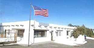 The white adobe-style hospital building with a flag out front